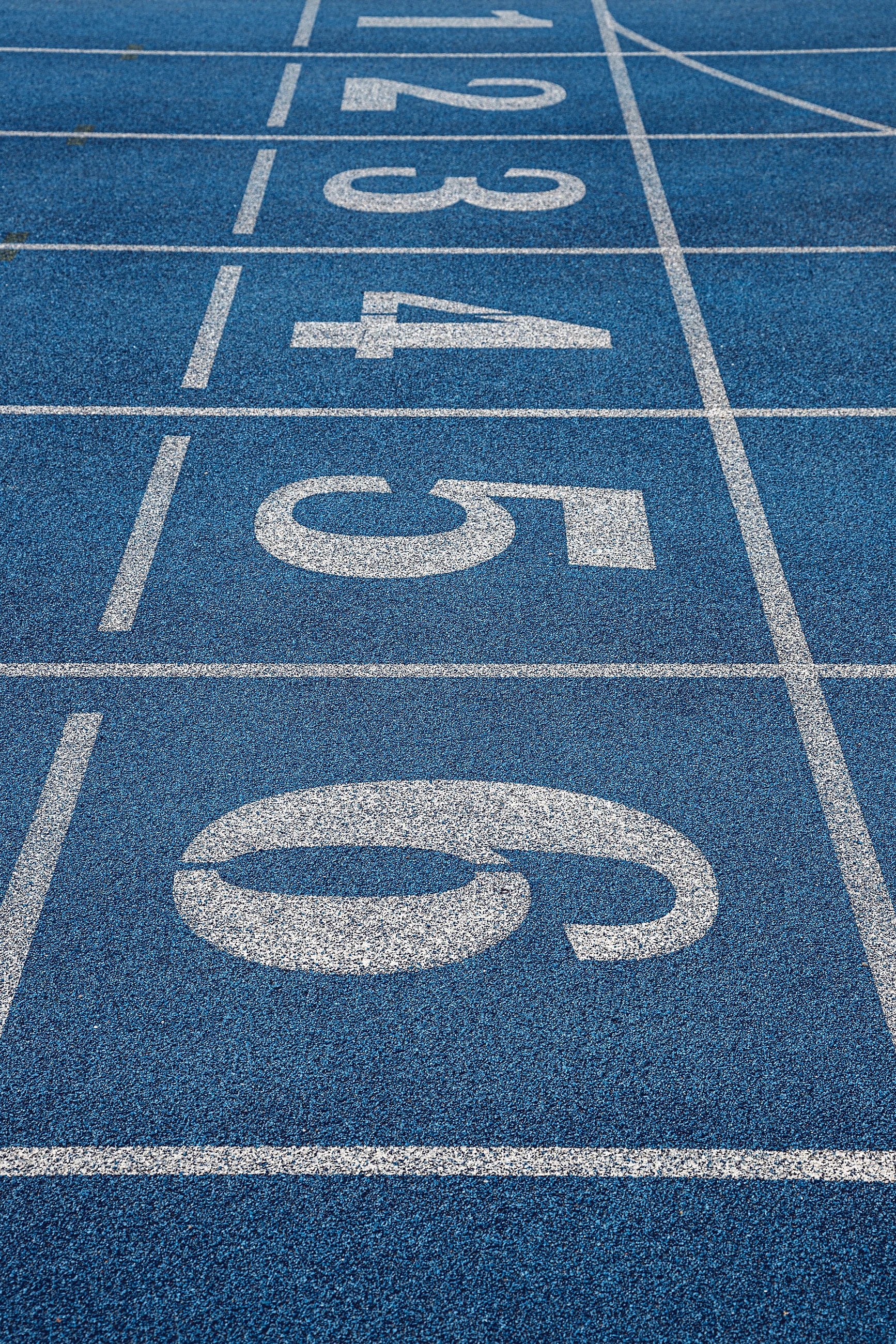 Lane seven of a running track, its painted number close up on the dark surface.
