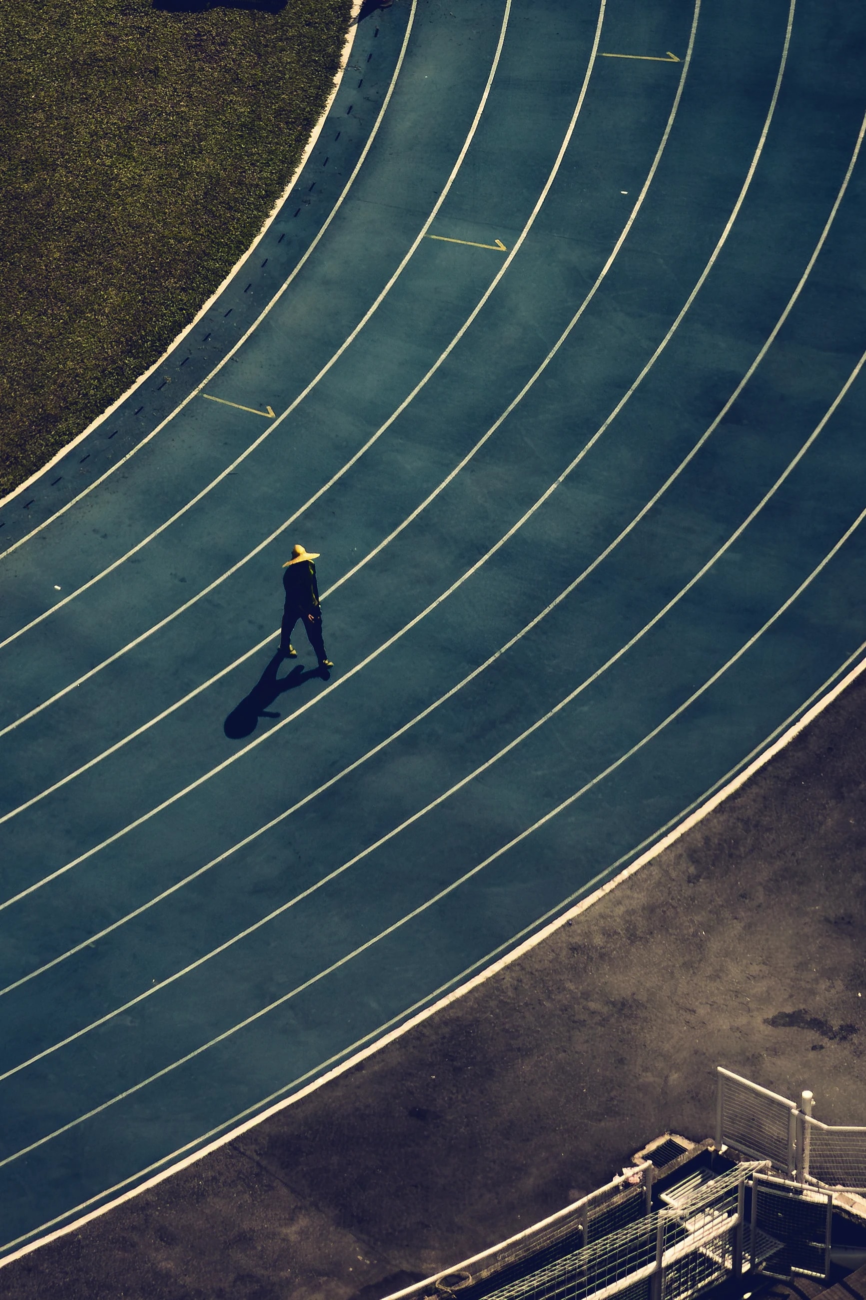 An athletics track seen from above, its lanes curving through the bend under dark light.